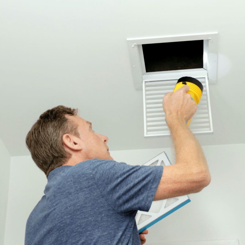 A person inspecting an air duct